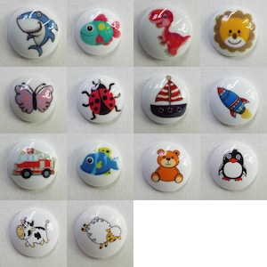 May include: Twelve round white ceramic buttons with various colourful cartoon images, including a shark, a fish, a ladybug, a boat, a rocket, a fire engine, a penguin, a teddy bear, a cow, a sheep, a dinosaur, and a lion.