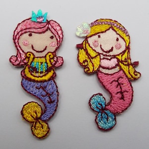 May include: Two embroidered mermaid patches. One mermaid has pink hair and a purple tail with a yellow crown. The other mermaid has yellow hair and a pink tail with a blue and white shell.