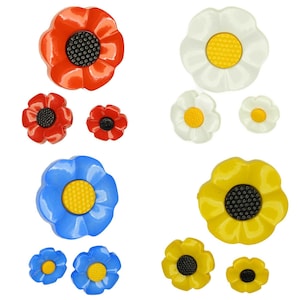 May include: Set of nine plastic flower buttons in red, white, blue, and yellow. The buttons have a raised centre with a black dot and a textured centre.