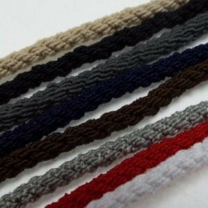 May include: A collection of braided cords in various colours, including beige, grey, navy blue, brown, light grey, red, and white. The cords are arranged in a layered pattern, showcasing their different textures and colours.