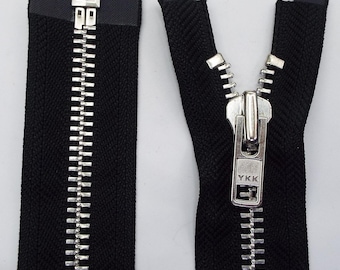 May include: A black zipper with a silver metal slider and teeth. The zipper is open and the slider has the brand name "YKK" printed on it.