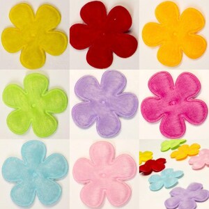 May include: Assortment of ten felt flower embellishments in various colors, including yellow, red, green, purple, pink, and blue. Each flower has six petals and a small center circle.