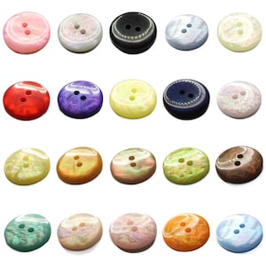 May include: Assortment of 20 two-hole round buttons in various colours and patterns, including iridescent, solid, and speckled finishes.