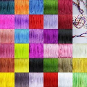 May include: A collection of 36 spools of colourful embroidery floss, arranged in a grid pattern. The floss is a variety of colours, including red, green, blue, yellow, pink, purple, and orange.