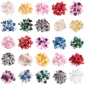 May include: Assortment of colourful fabric buttons in various shapes, including hearts, stars, and flowers. The buttons are arranged in rows on a white background.