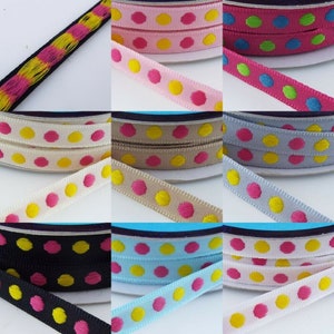 May include: Assortment of polka dot ribbon in various colours including pink, yellow, blue, green, grey, black and white. The ribbon has a yellow and pink polka dot pattern.