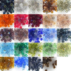 May include: Assortment of 24 colours of glass seed beads. Each colour is displayed in a separate square. The beads are small and round with a hole in the centre. The colours include clear, white, black, red, orange, brown, blue, green, and gold.