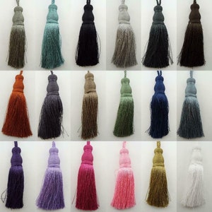 May include: Assortment of 20 tassel tiebacks in various colours, including white, black, red, green, blue, purple, and brown. The tassels are made of a soft, woven fabric and have a loop at the top for hanging.