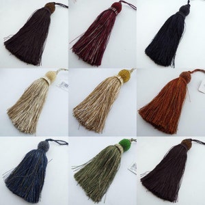 May include: Assortment of ten decorative tassels in various colours, including brown, burgundy, black, gold, orange, blue, and green. Each tassel features a small, round bead at the top.