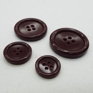 May include: Four burgundy plastic buttons with four holes each. The buttons are different sizes.