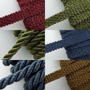 May include: Assortment of braided trim in various colours, including red, green, blue, and brown. The trim is woven with a subtle shimmer and has a textured, rope-like appearance.