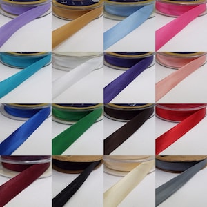 May include: A collection of 18 spools of satin ribbon in various colours, including purple, gold, light blue, pink, turquoise, white, dark purple, peach, blue, green, brown, red, burgundy, black, cream, and grey.