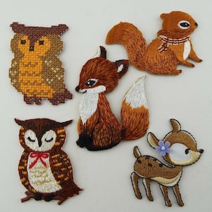 May include: Five embroidered iron-on patches featuring woodland animals: a brown owl with closed eyes, a brown owl with open eyes, a red fox, a brown squirrel, and a brown deer with a purple flower.