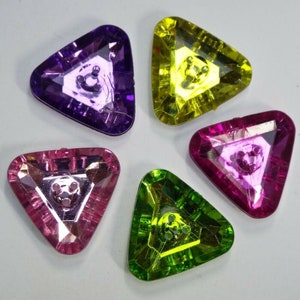 May include: Four triangular shaped buttons with a faceted design. The buttons are in the colours purple, yellow, pink, and green.