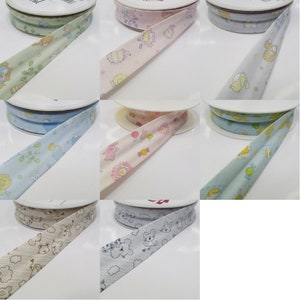 May include: Nine spools of fabric trim with different colourful patterns featuring cartoon animals, flowers, and candy. The trim is on white spools.