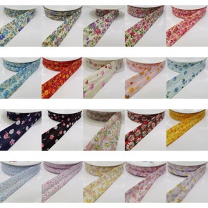 May include: A collection of 15 spools of floral patterned ribbon. The ribbon is in various colours, including blue, red, yellow, pink, and white. The ribbon is on white spools.