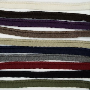 May include: A collection of 12 different coloured cotton cords, each with a braided texture. The cords are arranged in rows, with the colours ranging from white to dark green.