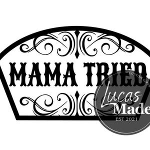 以下が含まれることがあります： 「MAMA TRIED」の文字が太字で書かれた白黒のサイン。装飾的なスクロールワークで縁取られています。右側には「Lucas Made」と「EST 2021」の円形ロゴがあります。サインは扇形です。