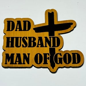 May include: Wooden sign with a black cross and the text "DAD HUSBAND MAN OF GOD".