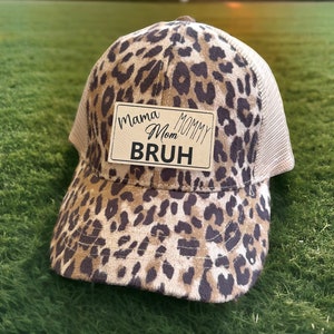 Könnte beinhalten: Eine braune und schwarze Trucker-Kappe mit Leopardenmuster und einem braunen Patch mit der Aufschrift "Mama Mom Mommy BRUH".
