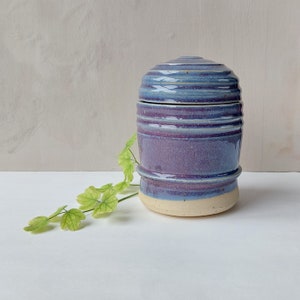 Handmade urn with lid on turntable. Ceramic pot with lid.