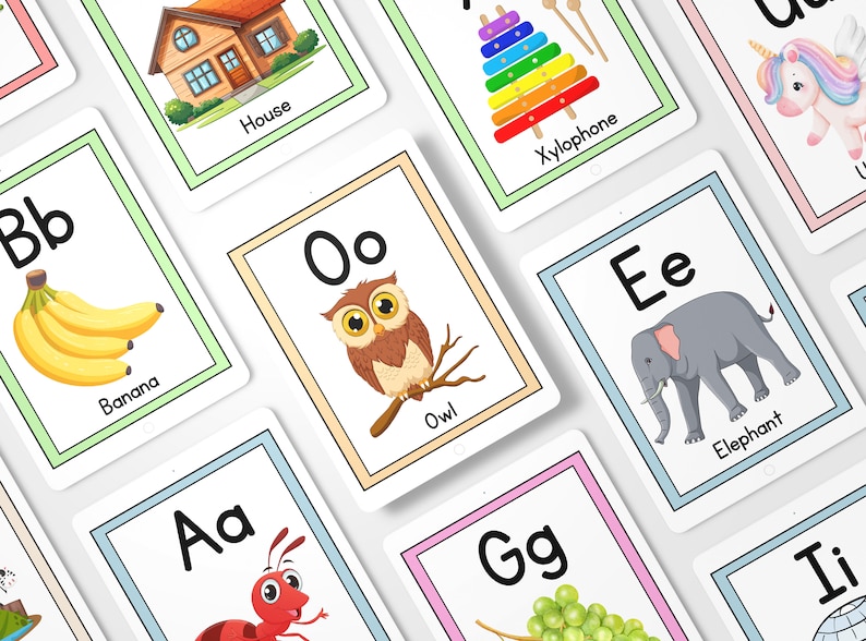 Op de afbeelding: Een set alfabetkaarten met kleurrijke illustraties van verschillende voorwerpen en dieren. Elke kaart heeft een letter van het alfabet in hoofdletters en kleine letters, samen met het bijbehorende woord. De letters zijn zwart, en de woorden zijn zwart. De illustraties zijn kleurrijk en cartoonachtig. De kaarten zijn perfect om kinderen het alfabet en basiswoordenschat te leren.