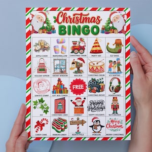 May include: A Christmas Bingo game card with a red and green striped border. The card features festive illustrations and the words "Christmas Bingo" in a colorful font. The card is held by two hands.