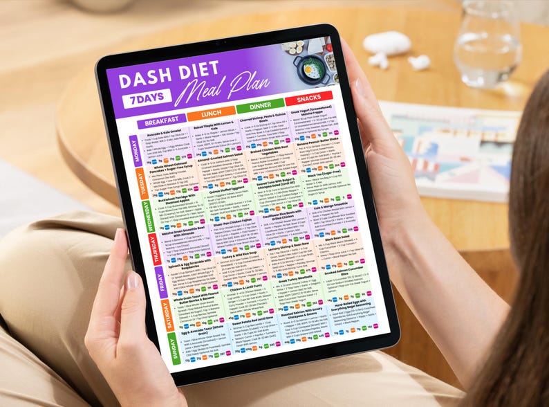 May include: A tablet displaying a 7-day DASH diet meal plan. The screen features a purple banner with the text "DASH DIET Meal Plan" and a colorful grid detailing breakfast, lunch, dinner, and snack options for each day of the week.