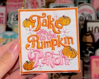 May include: White embroidered patch with orange text that says "Take Me to the Pumpkin Patch". The text is surrounded by orange pumpkins and pink flowers.
