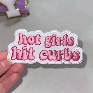 May include: Pink embroidered iron-on patch with the text "hot girls hit curbs" in a retro font style.