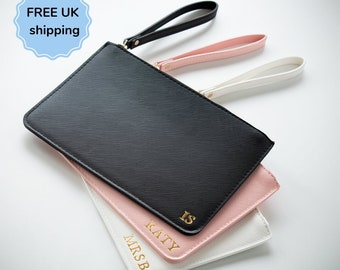 May include: Three personalized leather clutches in black, pink, and white with gold lettering. The clutches have a zipper closure and a wrist strap. The names "MRS B", "KATY", and "IS" are written on the clutches.