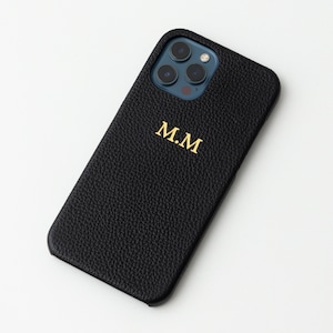 May include: Black leather phone case with a gold monogram "M.M."