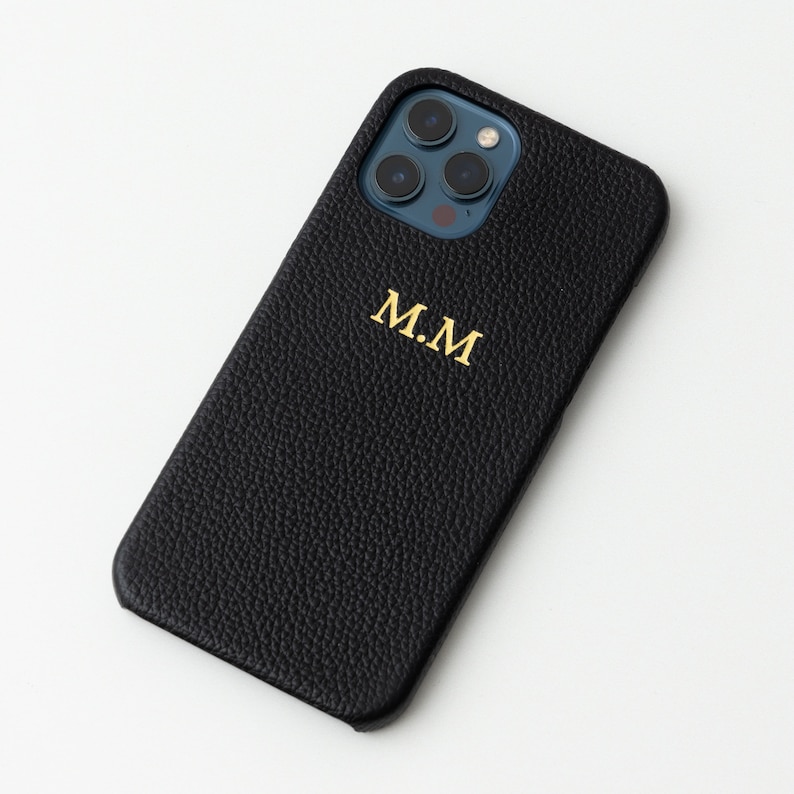 May include: Black leather phone case with a gold monogram "M.M."