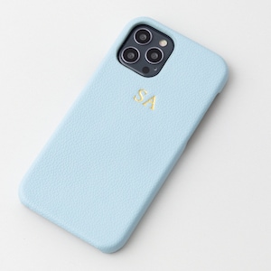 May include: A light blue leather phone case with a gold monogram "SA" and a black camera lens cutout.