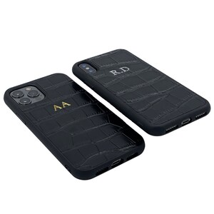 May include: Two black leather phone cases with a crocodile pattern. One case has the initials "AA" embossed in gold and the other case has the initials "RD" embossed in gold.
