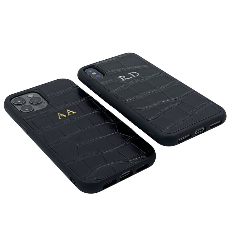 May include: Two black leather phone cases with a crocodile pattern. One case has the initials "AA" embossed in gold and the other case has the initials "RD" embossed in gold.