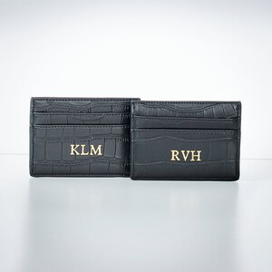 K&ouml;nnte beinhalten: Zwei schwarze Lederkartenhalter mit gepr&auml;gtem Krokodilmuster. Der Kartenhalter links tr&auml;gt die Initialen "KLM" in goldenen Buchstaben. Der Kartenhalter rechts tr&auml;gt die Initialen "RVH" in goldenen Buchstaben.