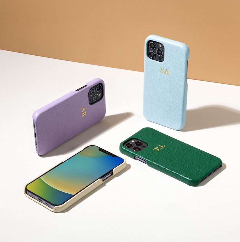 May include: Four phone cases, two in light blue, one in purple, and one in green, with initials "SA", "AB", and "TL" printed on them.
