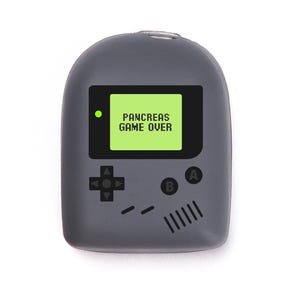 May include: A grey handheld device with a screen displaying "PANCREAS GAME OVER" in white text on a green background. The device has a classic game console design with directional buttons and A/B buttons.