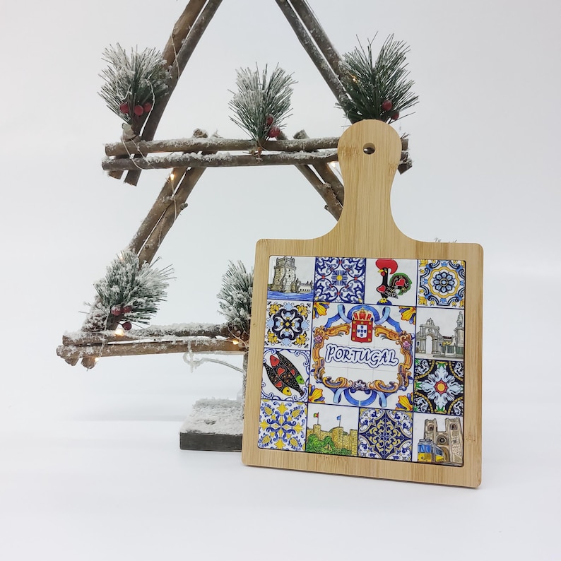 May include: A wooden cutting board with a handle, featuring a colorful design of Portuguese tiles and the word "Portugal".