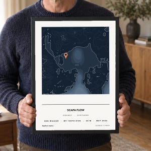 Könnte beinhalten: Ein gerahmter bathymetrischer Kartendruck von Scapa Flow, Orkney, Schottland, mit dunkelblauen Tiefenlinien, einer orangefarbenen Standortnadel und weißem Text mit Ben Walker, My 100th Dive, 38 m, Mai 2026 sowie geografischen Koordinaten.