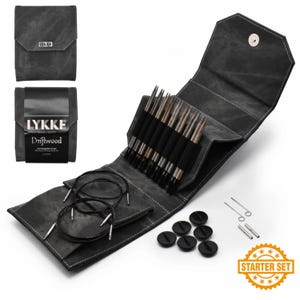 May include: A dark gray Lykke Driftwood interchangeable knitting needle set. The set includes needles, cables, stoppers, and accessories, all stored in a matching gray case. The case is open, displaying the contents. The words "Starter Set" are printed on a gold starburst.
