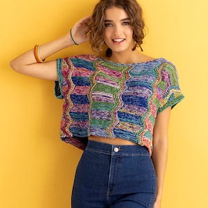 Puede incluir: Un top de crochet colorido, multicolor, con mangas cortas y de longitud recortada. El top está hecho con una variedad de colores, incluyendo azul, verde, morado y rosa. El top se lleva con jeans azules.