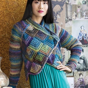 Könnte beinhalten: Ein mehrfarbiger Strickcardigan mit geometrischem Muster. Der Cardigan hat lange Ärmel und einen Wickelverschluss. Das Model trägt einen türkisfarbenen Rock.