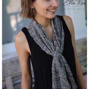 Puede incluir: Una mujer con un top negro sin mangas y una bufanda de punto gris y blanco. La bufanda está hecha de una mezcla de seda rústica. El texto "Ella Rae Rustic Silk" es visible en la esquina superior derecha de la imagen.