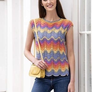 May include: A woman wearing a colourful crochet top with a wavy pattern. The top has a scoop neck and short sleeves. She is also wearing blue jeans and a small yellow crossbody bag.