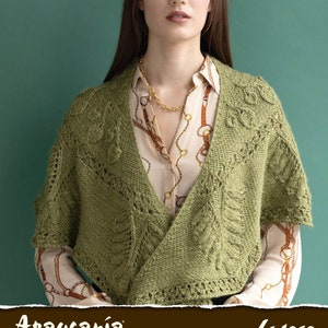 Pode incluir: Um xale de malha verde com um delicado padrão de renda. O xale está drapeado sobre uma pessoa que está vestindo uma blusa creme com um colar de corrente dourada. O texto "Araucanía Yarns" e "Lujoso" é visível na parte inferior da imagem.