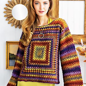 May include: A colorful crochet sweater with a square pattern in shades of purple, orange, yellow, and brown. The sweater has long sleeves and a loose fit.