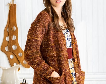May include: A brown cardigan with a speckled pattern and two pockets. The cardigan has a V-neck and button closure. The model is wearing a floral dress and a brown hat.