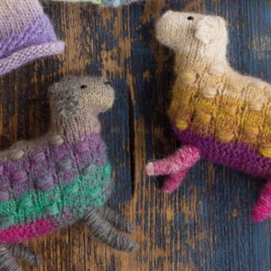 May include: Two knitted sheep toys, one with a purple, green, and pink color scheme and the other with a yellow, orange, and pink color scheme.